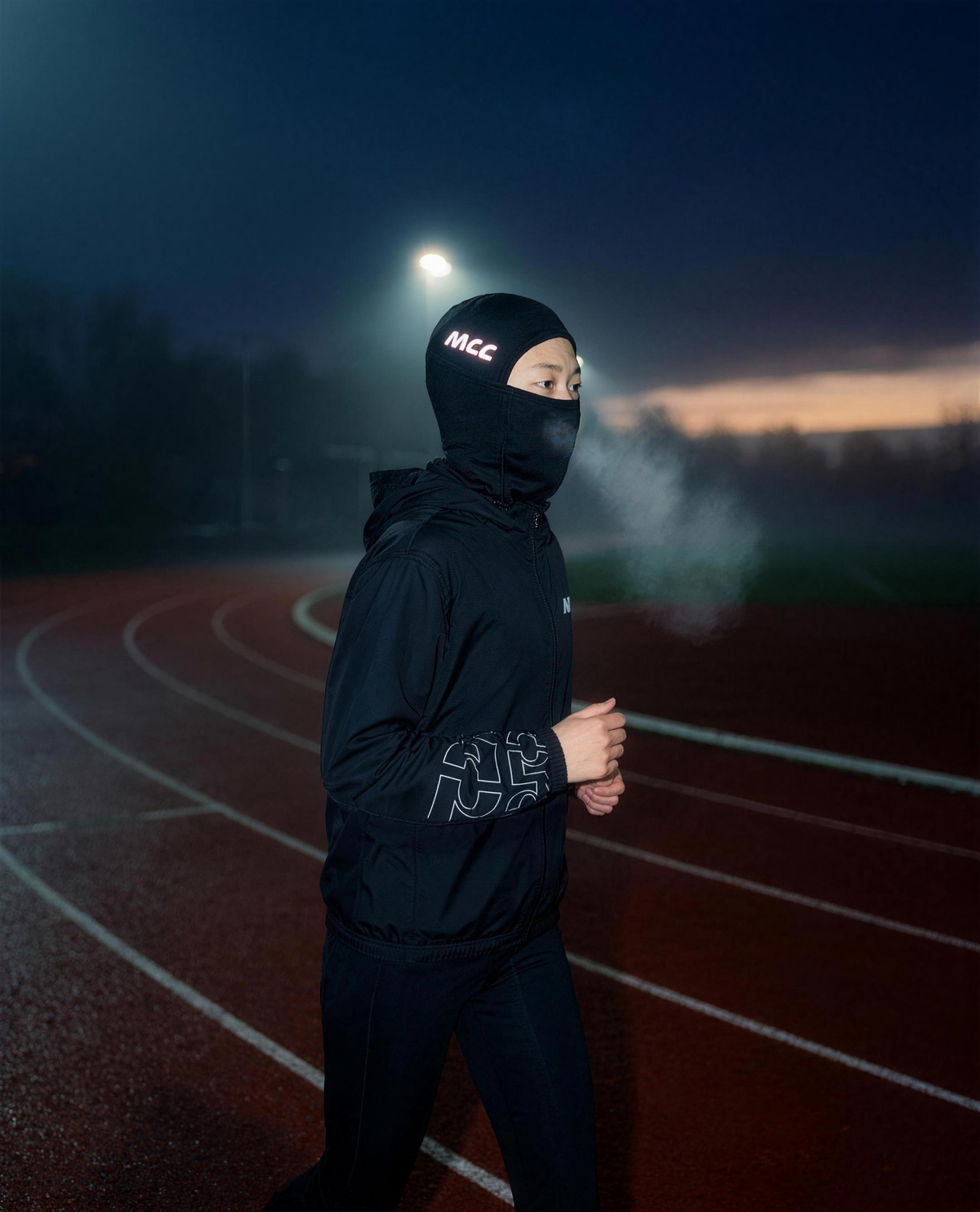 MCC 5-9 Active balaclava worn while running laps on a misty pre-dawn track, reflective MCC wordmark