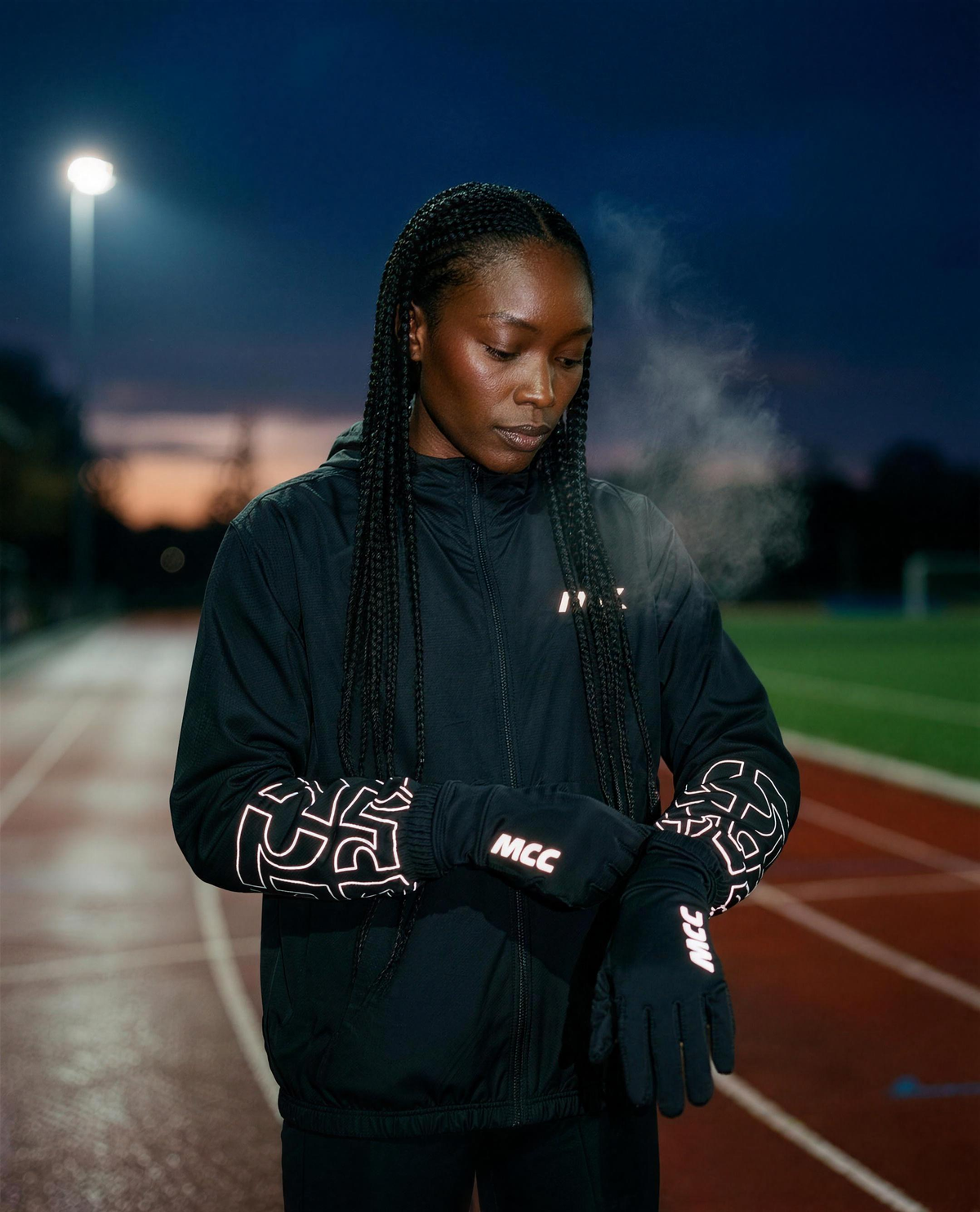 MCC 5-9 Active running gloves, pulling the cuff snug before a pre-dawn run, reflective MCC wordmark and reflective sleeve pattern